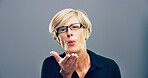 Blowing, kiss and portrait of mature woman with reaction for flirting, romance and affection on gray background. Happy, hand gesture and isolated person with emoji for love, dating and valentines day