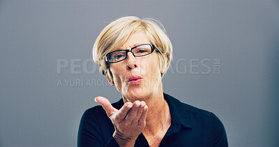 Buy stock photo Blowing, kiss and portrait of mature woman with reaction for flirting, romance and affection on gray background. Happy, hand gesture and isolated person with emoji for love, dating and mockup space