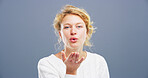 Woman, portrait and blowing with kiss for affection, love or romance on a gray studio background. Female person, face or blonde model with hand or romantic gesture for distant compassion on space