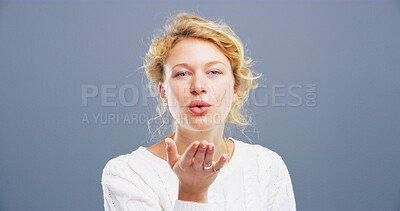 Buy stock photo Woman, portrait and blowing with kiss for affection, love or romance on a gray studio background. Female person, confident face or mockup with hand or romantic gesture for distant compassion on space