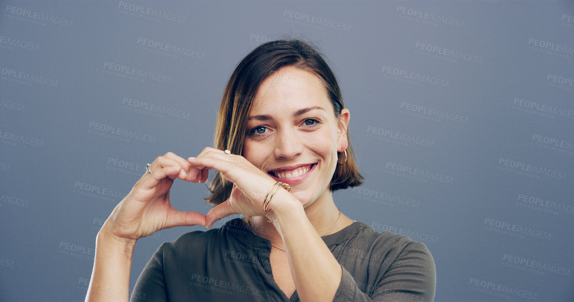 Buy stock photo Smile, portrait and woman with heart hands in studio for appreciation, kindness and support. Mockup, person and love gesture on gray background for affection, gratitude and motivation sign with pride