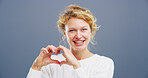 Heart, studio and portrait of woman with hand gesture for support, kindness and care. Space, confident and happy person with emoji, sign and hope for thank you, charity and love on blue background