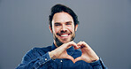 Hands in heart, studio and portrait of happy man with gesture for support, kindness and care. Smile, confident and person with emoji, sign and hope for thank you, charity and love on gray background