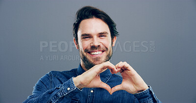 Buy stock photo Hands in heart, studio and portrait of happy man with gesture for support, kindness and care. Smile, confident and person with emoji, sign and hope for thank you, charity and love on gray background