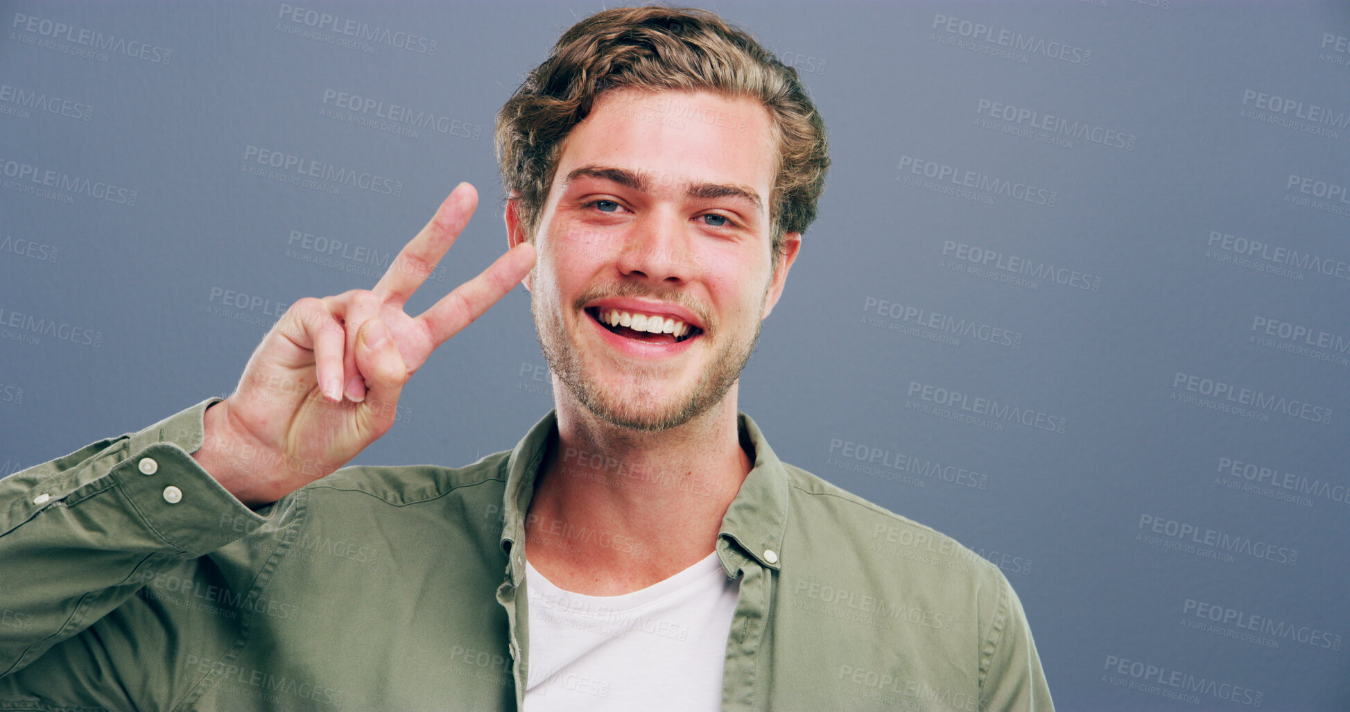 Buy stock photo Man, peace sign and smile in studio portrait, v icon and space by gray background. Model, person and excited with symbol, happy or pride with emoji in trendy fashion, style or hand gesture in Germany
