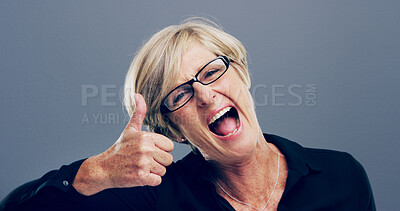 Buy stock photo Mature, excited woman and portrait with thumbs up for feedback, opinion or good job on a gray background. Female person, glasses or model with like emoji or yes sign in studio for positive approval