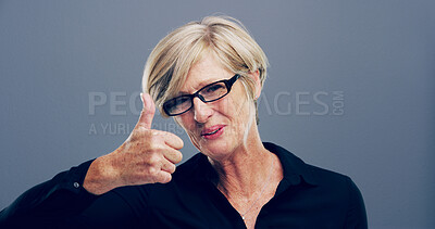 Buy stock photo Mature woman, portrait and thumbs up with smile for feedback, opinion or good job on a gray background. Female person, glasses or model with like emoji or yes sign in studio for positive approval