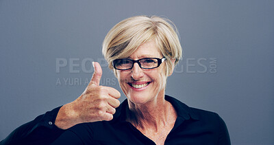 Buy stock photo Mature, happy woman or portrait with thumbs up for good job, feedback or opinion on gray background. Female person, glasses or model with like, emoji or yes sign in studio space for positive approval