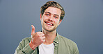 Happy man, portrait and feedback with thumbs up for good reaction on a gray studio background. Male person, model or smile with like emoji or yes sign for positive approval or satisfaction on space