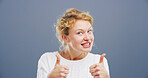 Happy woman, portrait or agreement with thumbs up for reaction on a gray studio background. Female person, model or smile with like emoji, gesture or yes sign for positivity, approval or satisfaction