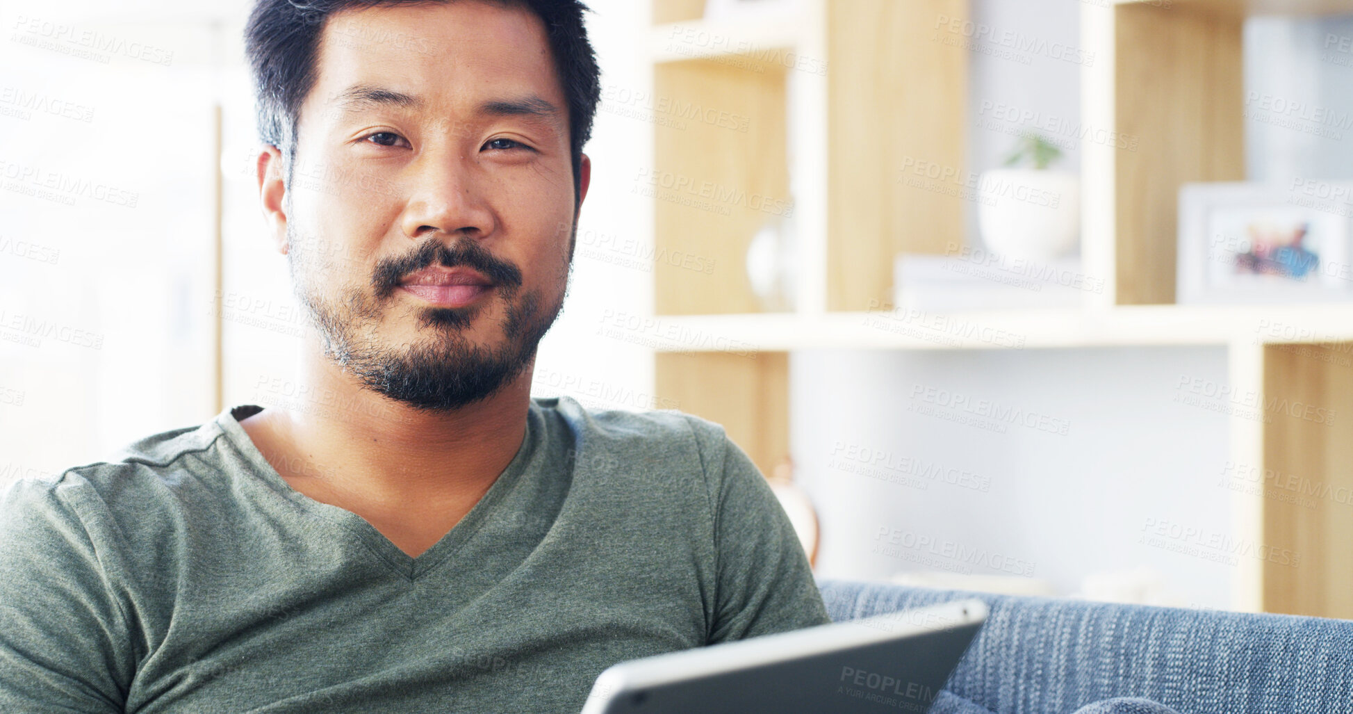 Buy stock photo Tablet, relax and portrait of Asian man on sofa for social media, streaming and networking app. Online post, newsletter and update with person in living room at home for chat, comment and contact