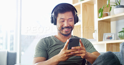 Buy stock photo Headphones, man and typing with phone in home for music search, streaming service and audio playlist. Relax, person and happy with smartphone on sofa for listening to radio app and podcast website