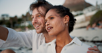 Buy stock photo Conversation, couple and relax with hug on beach, vacation holiday and bonding together for anniversary. Pointing, man and woman in interracial relationship for love embrace, travel or smile on ocean