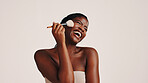 Brush, laughing and black woman in studio with makeup, beauty or cosmetics for getting ready. Happy, cosmetology and African female person with blush for facial color or glow by white background.