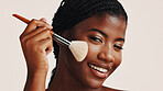 Brush, makeup and black woman in studio with face, beauty or cosmetics for getting ready. Happy, cosmetology and African female person with blush for facial color or glow by white background.