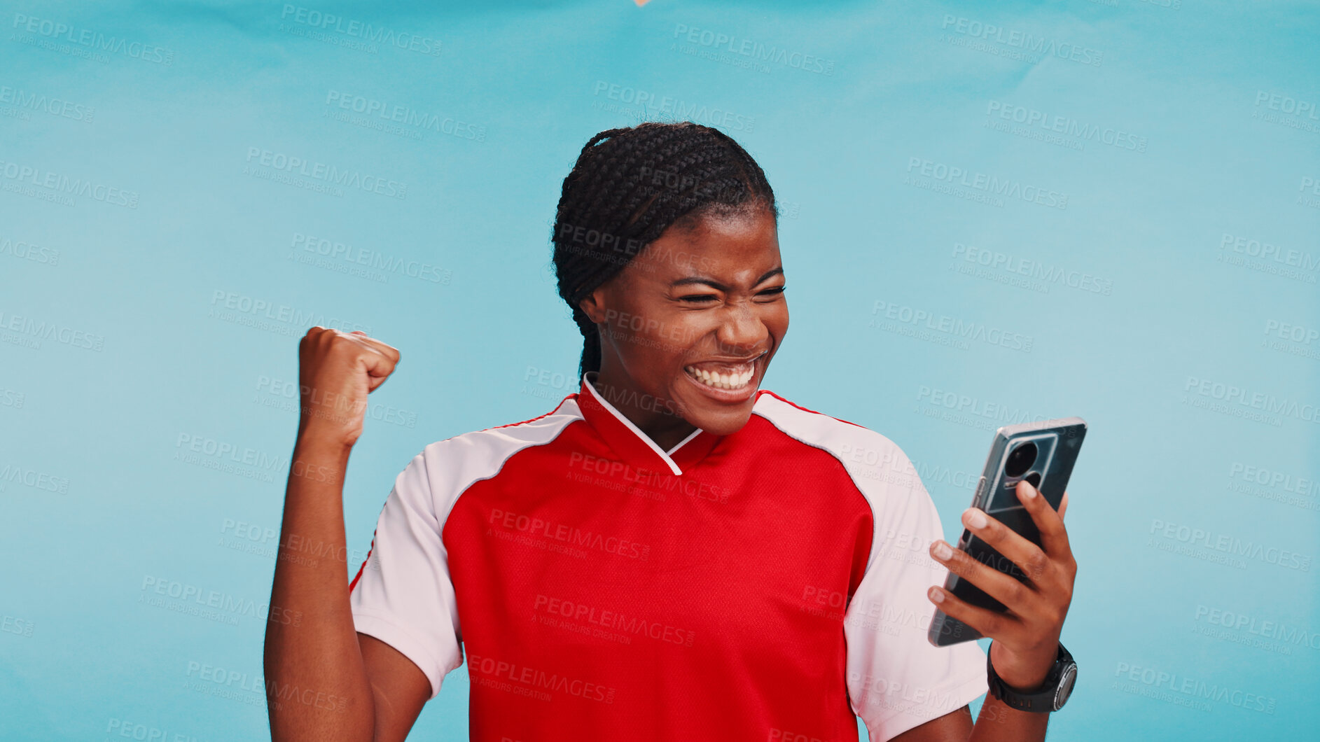Buy stock photo Black woman, phone and celebration in studio, sports and selection for soccer team by blue background. Girl, athlete and smartphone on mobile app, fist pump or cheers for success with draft results
