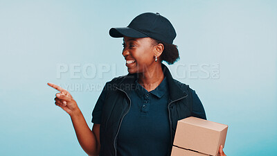 Buy stock photo Smile, black woman and pointing to space with shipping, box and logistics for mockup. African courier, happy and advertising with package for sales, promo or discount on blue studio background