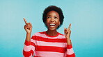 Black woman, pointing up and smile for advertising, promotion and presentation about us in studio. Information, news and notification with advice, review or feedback on blue background mockup space
