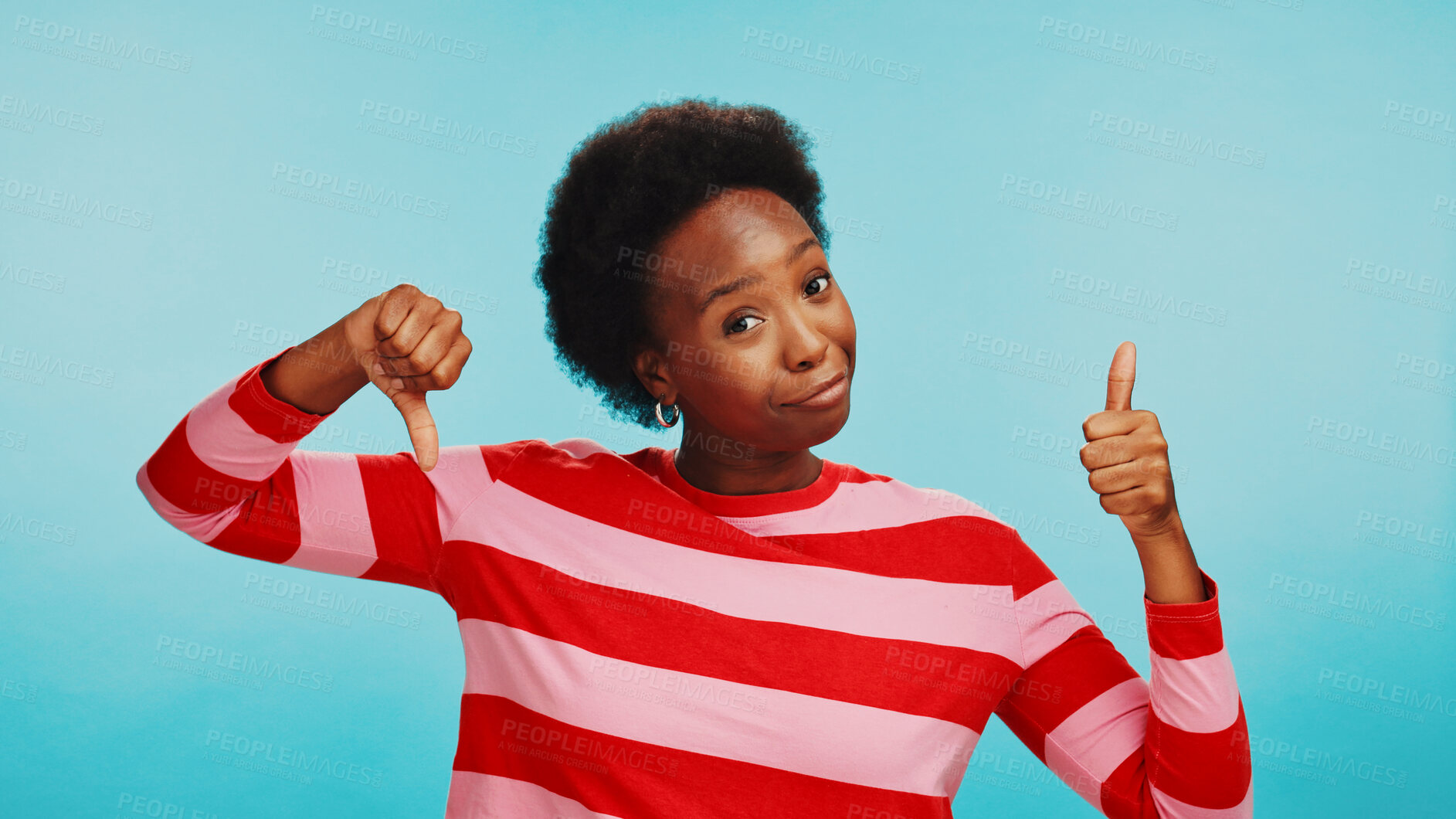 Buy stock photo Thumbs up, decision and black woman in studio for choice, selection and options on blue background. Mockup space, emoji and portrait of person with gesture and doubt for choosing, compare or confused