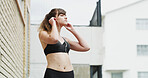 Earphones, fitness and woman in city for running, exercise or health activity with listening to music. Sports, audio tech and female athlete streaming workout playlist for cardio in urban town.