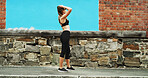 Girl, runner and tired with earphones in city by wall, space and streaming with sound, subscription and exercise. Woman, audio and profile with music for fitness, training or fatigue on road in Italy