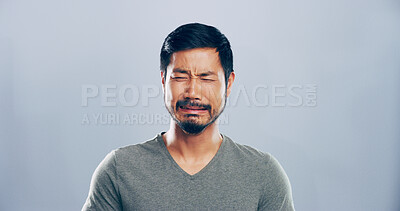 Buy stock photo Sad, Asian man and crying emotions in studio for mourning loss, broken heart and bad news. Mockup space, grief and person with depression, mental health and ptsd with trauma memory on gray background