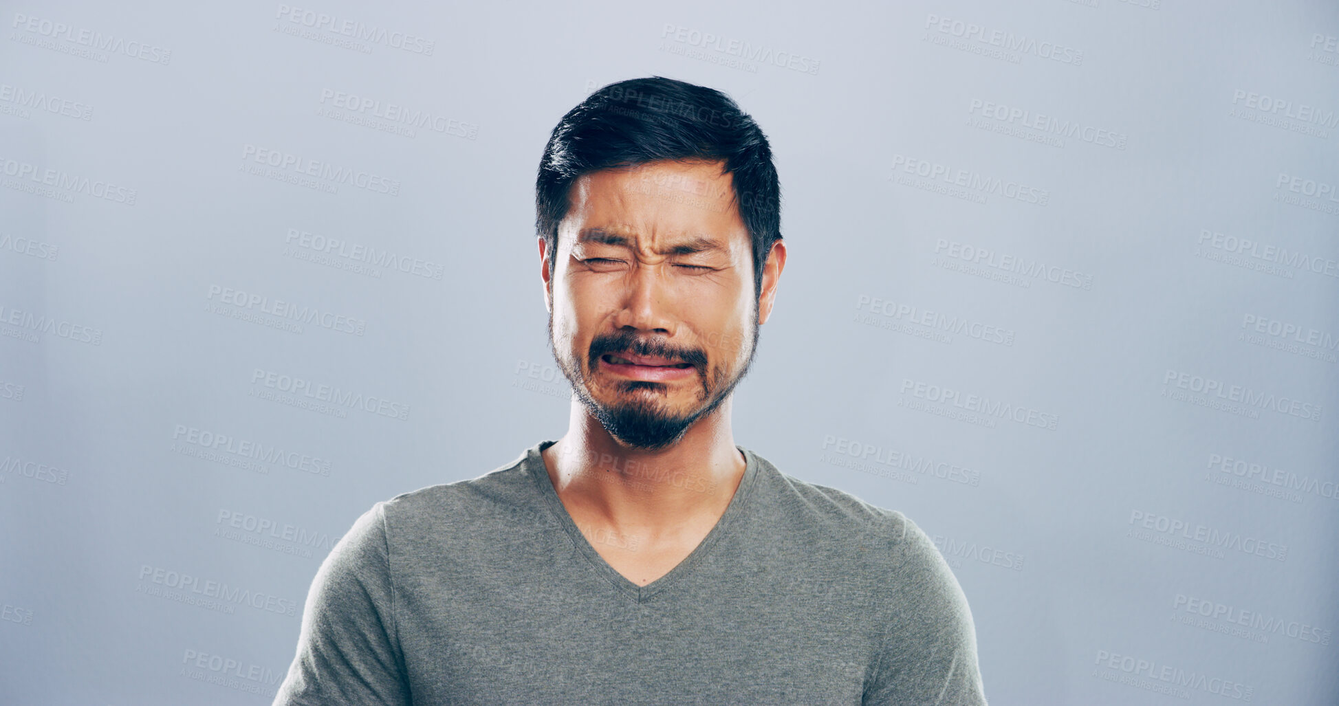 Buy stock photo Sad, Asian man and crying emotions in studio for mourning loss, broken heart and bad news. Mockup space, grief and person with depression, mental health and ptsd with trauma memory on gray background