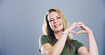 Heart hands, portrait and space with happy woman in studio for affection, love or romance. Emoji, smile and social media with flirty person on gray background mockup for health or wellness gesture