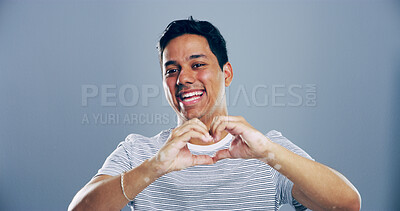Buy stock photo Heart hands, laughing and portrait with happy man in studio for affection, love or romance. Emoji, funny and social media with flirty person on gray background mockup for health or wellness gesture