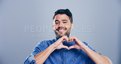 Buy stock photo Heart hands, portrait and smile with happy man in studio for affection, love or romance. Emoji, social media and symbol with flirty person on gray background mockup for health or wellness gesture