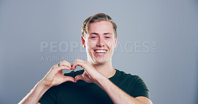 Buy stock photo Heart hands, portrait and space with smile of man in studio for affection, love or romance. Emoji, happy and social media with flirty person on gray background mockup for health or wellness gesture