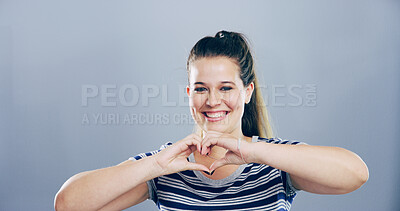 Buy stock photo Heart hands, portrait and smile with woman in studio for affection, love or romance. Emoji, flirting and social media with happy person on gray background mockup for health or wellness gesture