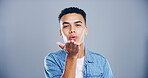 Portrait, man or blowing with kiss for love, affection or romance on a gray studio background. Creative, male person or model with romantic gesture or palm for care, distance or flirt on mockup space