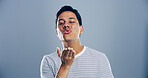 Portrait, man and blowing kiss with wink for romance, affection or love on a gray studio background. Creative, male person or model with romantic gesture or palm for distance or flirt on mockup space