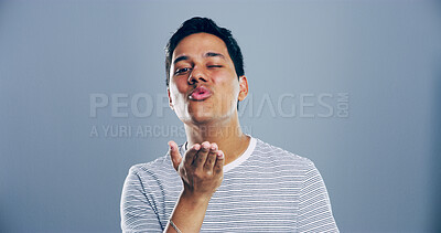 Buy stock photo Portrait, man and blowing kiss with wink for romance, affection or love on a gray studio background. Creative, male person or model with romantic gesture, palm for distance or flirt on mockup space