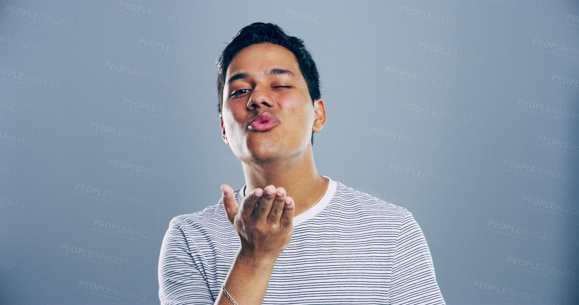 Buy stock photo Portrait, man and blowing kiss with wink for romance, affection or love on a gray studio background. Creative, male person or model with romantic gesture, palm for distance or flirt on mockup space