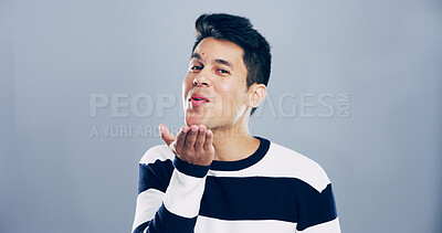 Buy stock photo Portrait, man and blowing kiss with flirt for love, affection or greeting on a gray studio background. Male person, student or model with care, palm or romantic gesture in distance on mockup space