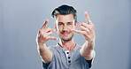 Rock, hands and portrait of man in studio with gesture for emoji, heavy metal and edgy attitude. Mockup space, rebel and face of person with punk sign, symbol and devil horns on gray background