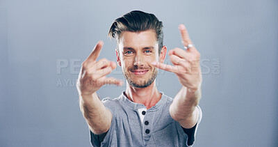 Buy stock photo Rock, hands and portrait of man in studio with gesture for emoji, heavy metal and edgy attitude. Mockup space, rebel and face of person with punk sign, symbol and devil horns on gray background