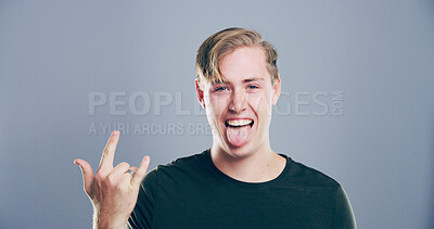 Buy stock photo Crazy, studio or portrait of happy man with rock hand gesture and tongue out isolated on gray background. Space, edgy rocker and male person with devil horn sign, funky emoji and wild punk symbol