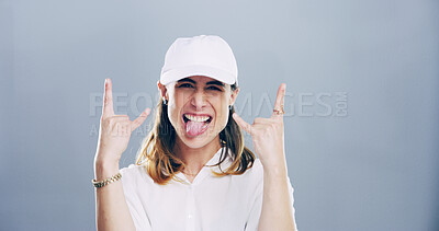 Buy stock photo Happy woman, portrait and model with rock on sign in studio for cool mood on a gray background. Face, female person or hand gesture with tongue out for devil horns, metal or funky expression on space