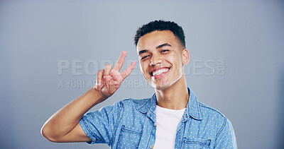 Buy stock photo Portrait, confident and happy man with peace sign in studio with positive attitude, mockup space or facial expression. Gray background, casual and proud male model for cool gesture, fashion or symbol