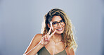 Portrait, peace sign and woman in studio, icon and kindness on blue background. Face, person and model with hand gesture, support and glasses with symbol, good vibes and emoji with smile and joy
