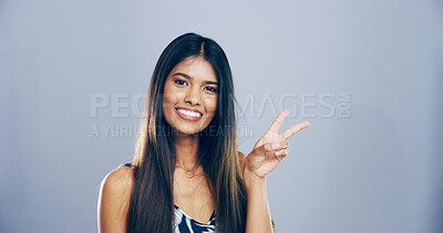 Buy stock photo Portrait, peace sign and woman in studio, smile and confidence on blue background. Face, person and model with hand gesture, support and agreement with symbol, good vibes and emoji with icon