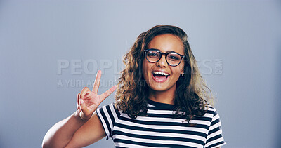 Buy stock photo Portrait, peace sign and woman in studio, happiness and confidence on blue background. Face, person and model with hand gesture, support and emoji with symbol, good vibes and icon with smile