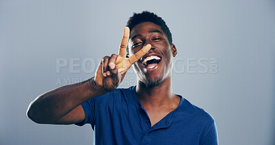 Buy stock photo Portrait, casual and happy black man with peace sign in studio with positive attitude or mockup space. Grey background, laughing or face of African male model for cool gesture, confidence or v symbol