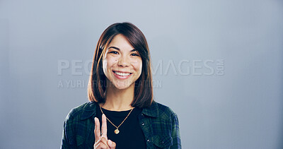 Buy stock photo Portrait, peace sign or woman with symbol, smile and confidence in studio. Face, happy person or model with hand gesture, support or agreement with good vibes, icon and emoji on gray background space