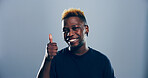 Happy, black man or portrait with thumbs up for success or positive feedback on a gray studio background. Face, male person or model with smile, like emoji or yes sign for approval on mockup space