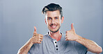 Happy man, portrait and thumbs up with emoji for success or approval on a gray studio background. Face, male person or model with smile, like hand gesture or yes sign for winning on mockup space