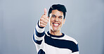 Portrait, thumbs up and man in studio, smile and confidence on gray background. Face, happy person and model with hand gesture, agreement and icon with symbol, perfect and like with emoji and review